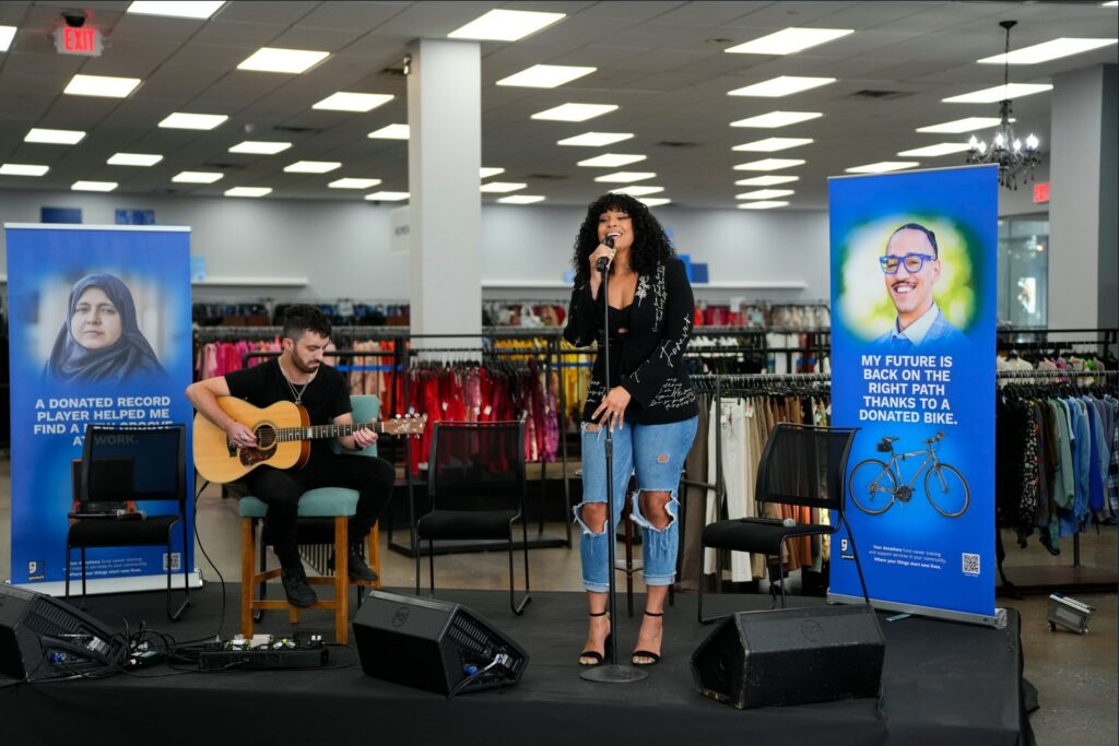 A picture of Jordin Sparks and her band guitarist performing at a local Goodwill store.
