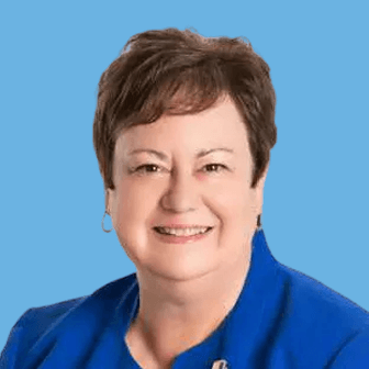 Smiling woman in a blue blazer against a solid blue background