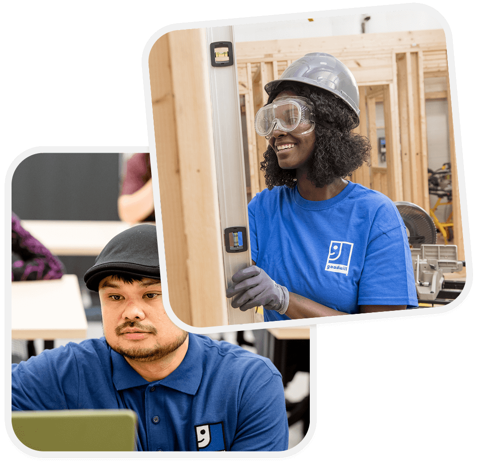 Smiling woman in hard hat and safety goggles stands beside a wooden frame while a man in a blue Goodwill polo works on a laptop.