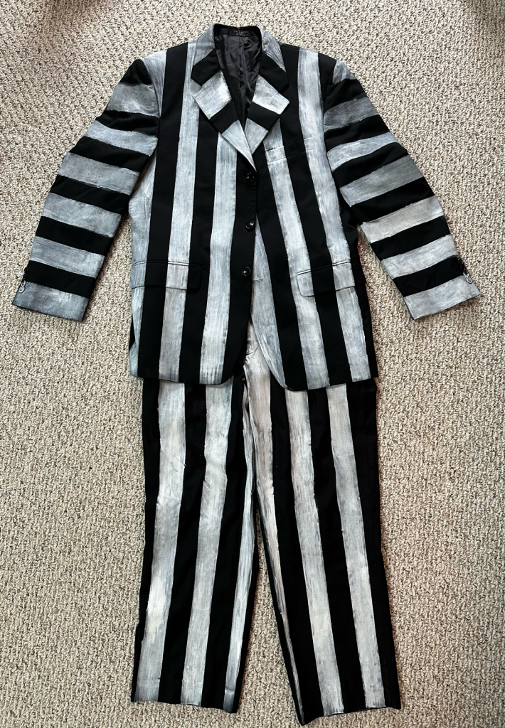 Bold black and silver striped blazer with matching pants laid on beige carpet.