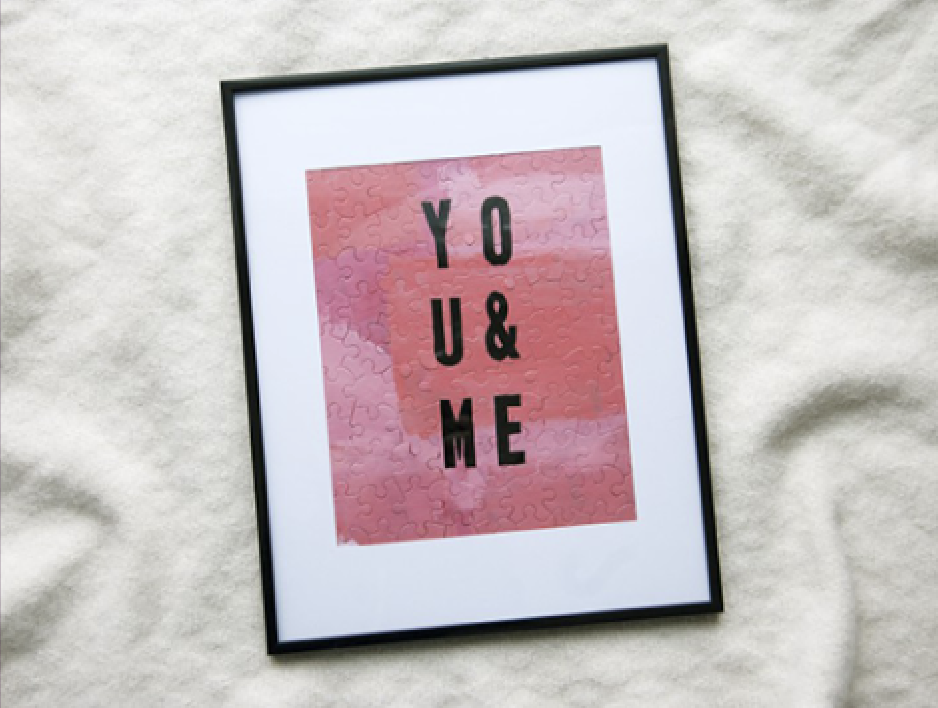 Framed print with a pink puzzle-piece background showing the words YOU & ME in bold black letters arranged in three vertical lines.