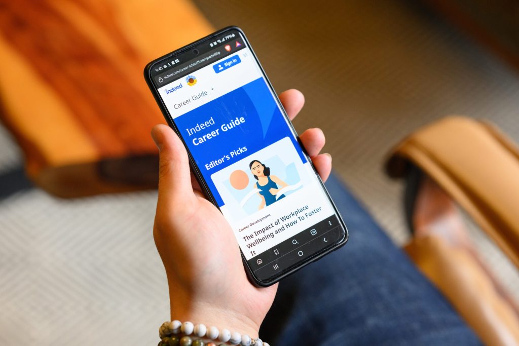 Hand holding a smartphone displaying the Indeed Career Guide page on the screen.