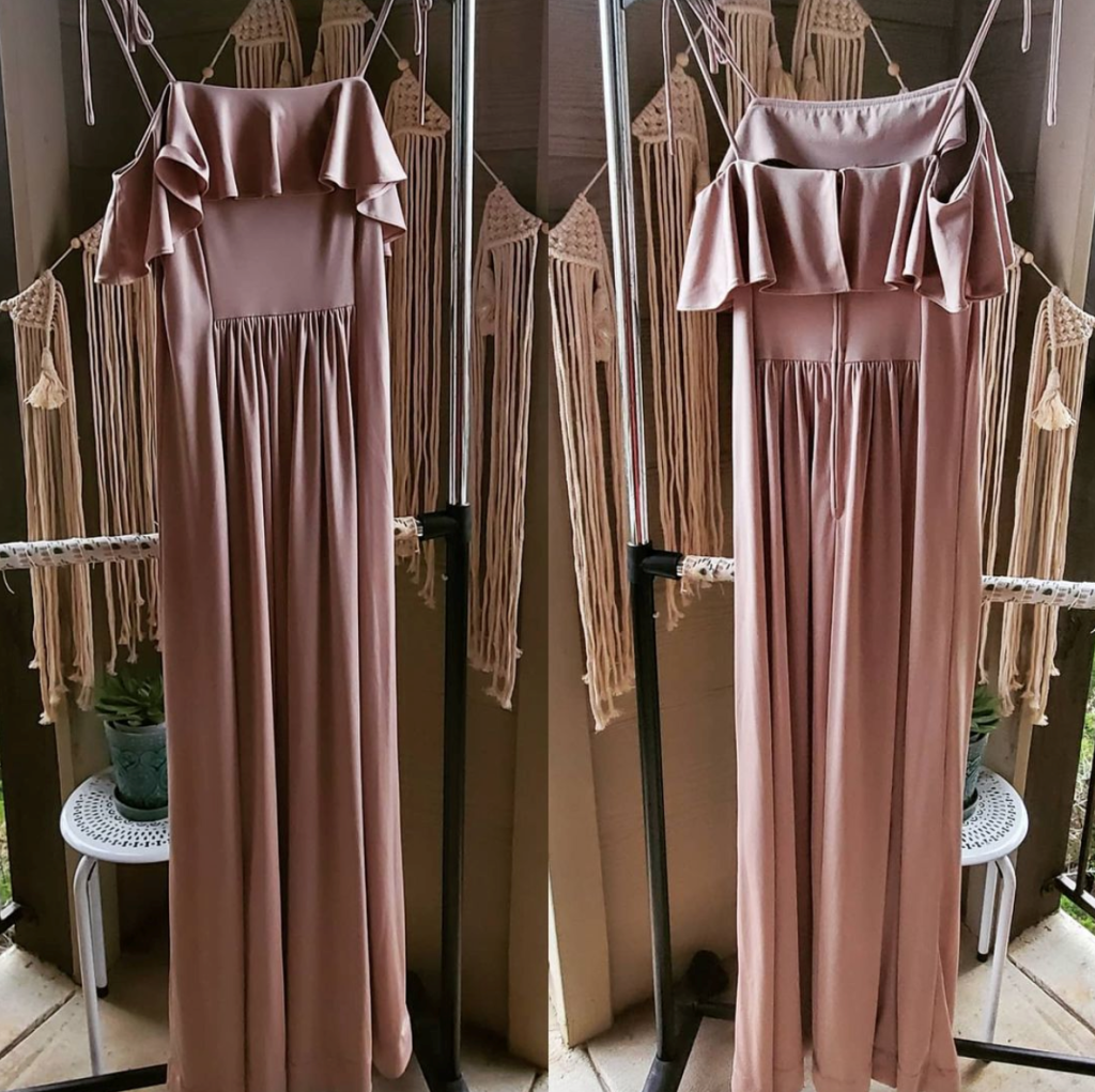 Long mauve off-shoulder maxi dress with a ruffled bodice on a clothes stand, set against macrame backdrop.