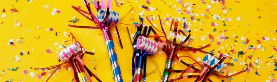 Colorful party poppers with confetti on a bright yellow background.