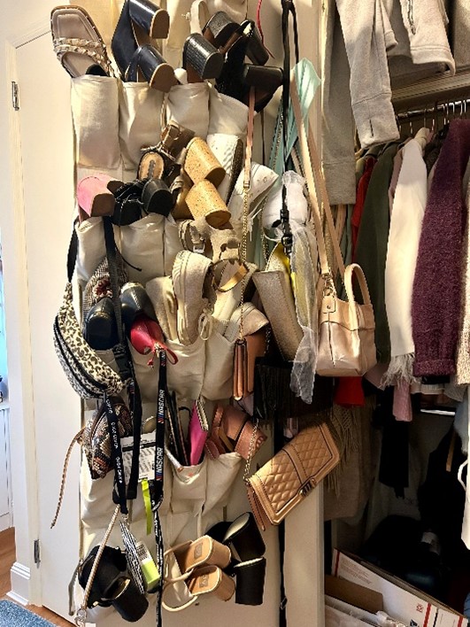 Closet cluttered with handbags, sandals, and accessories hanging on a rack beside clothes.