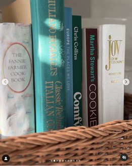 Row of cookbook spines in a woven basket on a shelf, featuring The Fannie Farmer Cook Book and Martha Stewart's Cookies.