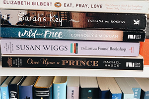 Stack of paperback novels on a shelf, featuring Eat, Pray, Love and other popular titles.