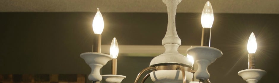 Elegant white chandelier with multiple glowing candle bulbs indoors