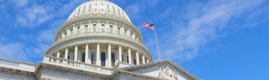 U.S. Capitol dome with American flag against a clear blue sky