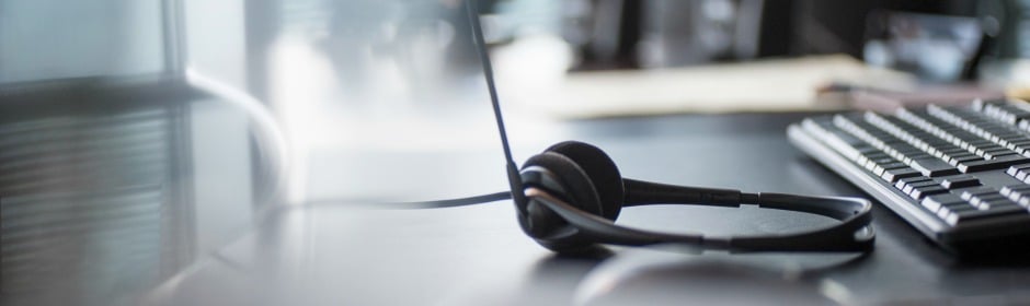 Headset with microphone resting on a desk beside a computer keyboard