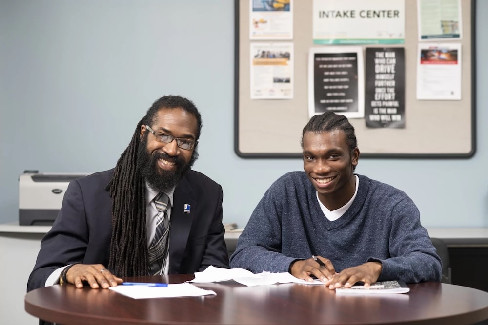 Mentor and student collaborating at a round table in a campus office.