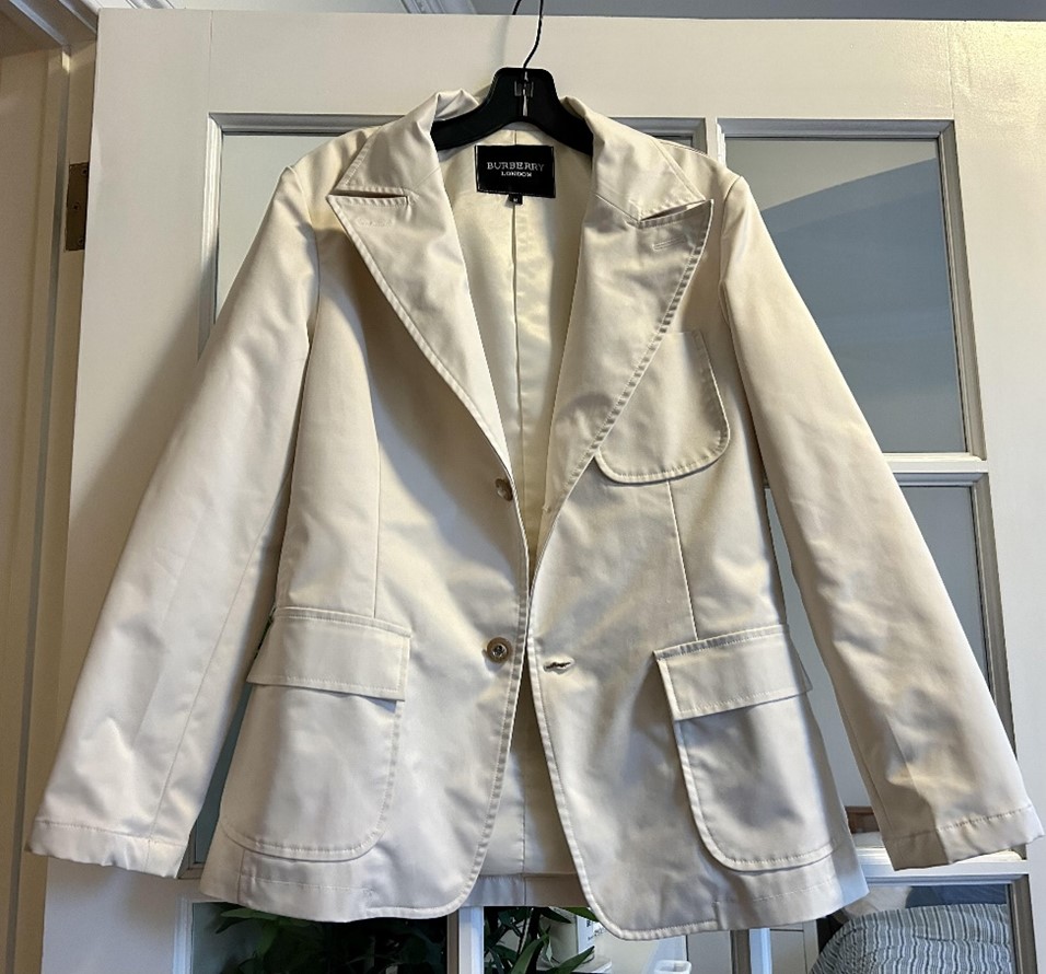 A white blazer hanging by a hanger in a door