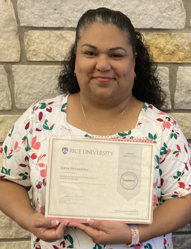 Woman in a floral blouse holding a Rice University certificate against a stone wall.