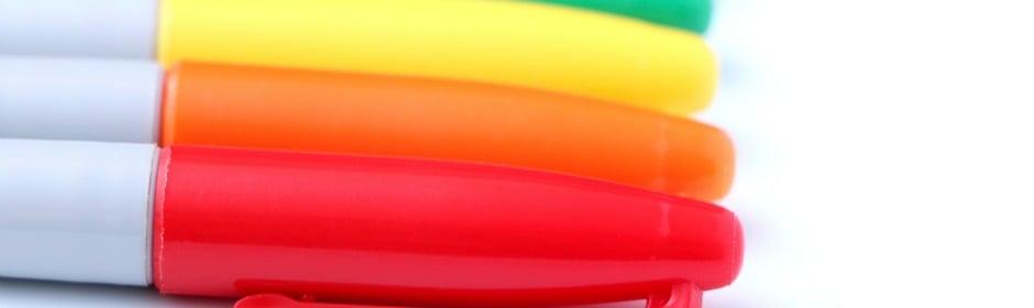 Close-up of colored marker pens arranged diagonally on a white surface.