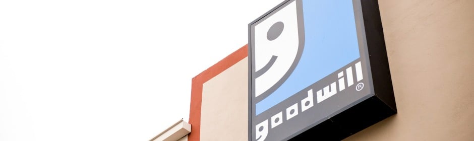 Tilted view of a Goodwill storefront sign mounted on a beige building.