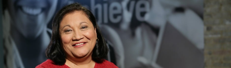 Smiling woman in red sweater against a blurred backdrop.