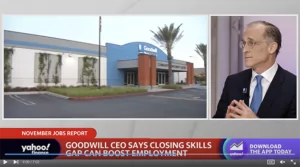 Exterior view of a Goodwill storefront beside a palm tree during a news broadcast.