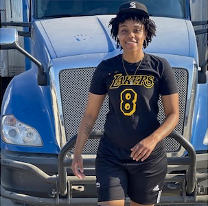 Young woman in a Lakers jersey (#8) standing in front of a blue truck.