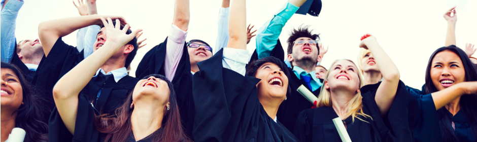 Group of graduates in caps and gowns celebrating with raised hands.