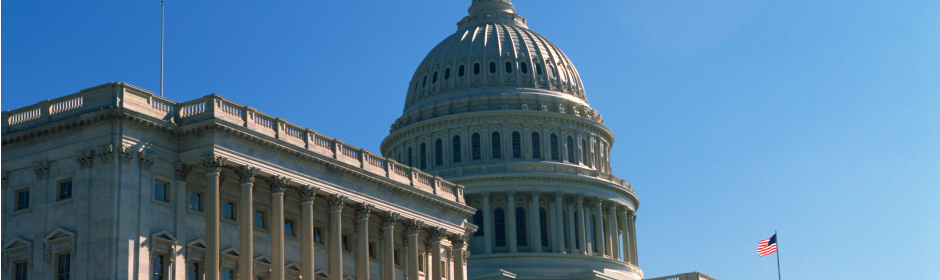 U.S. Capitol dome with neoclassical facade under a bright blue sky.