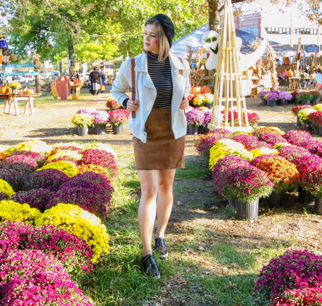 Woman walking between colorful potted chrysanthemums at an outdoor flower market.