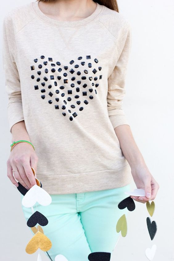 Beige sweater with a dotted heart pattern and mint pants, holding a string of paper hearts.
