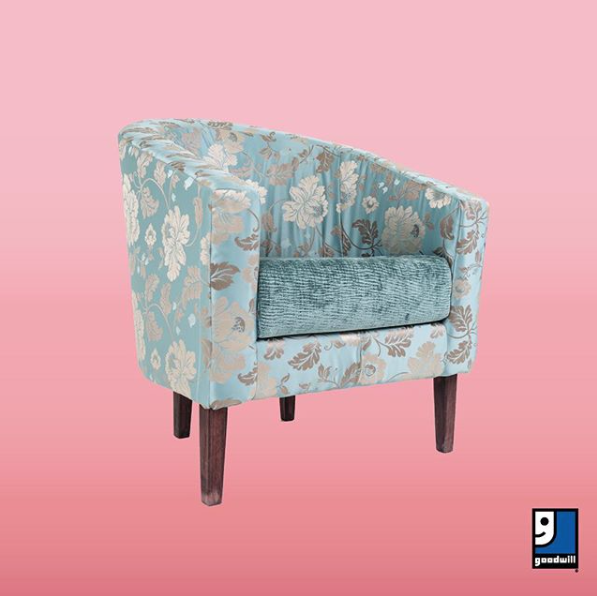 Blue floral upholstered armchair with a teal cushion on a pink gradient background