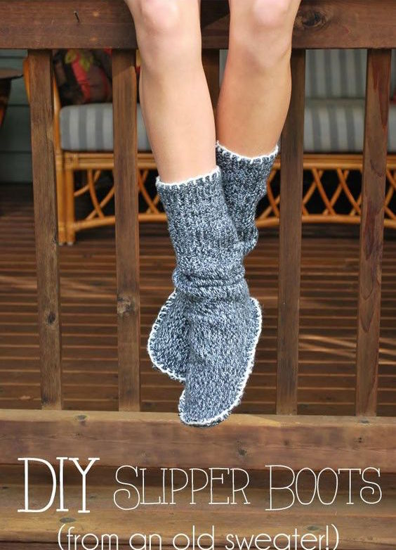Person wearing cozy gray knitted slipper boots draped over a wooden railing.