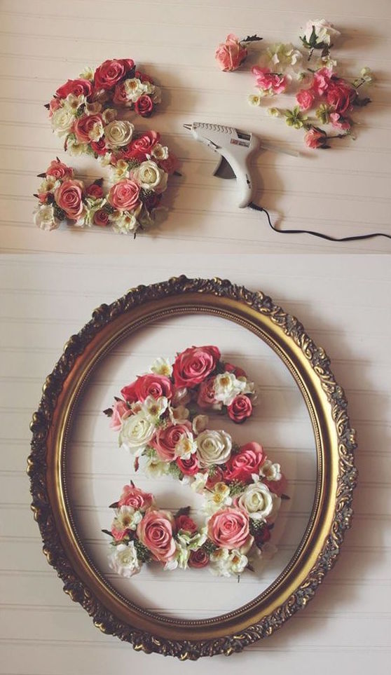 S-shaped arrangement of pink and white roses with a hot glue gun nearby and an ornate oval frame.