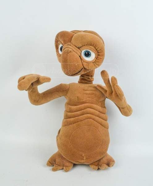 Brown plush dragon hand puppet with large blue eyes, raised arms, and a ribbed torso against a light background.