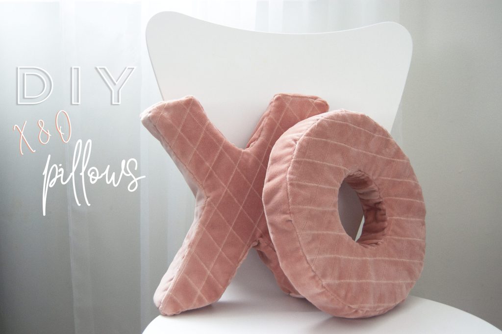 Soft pink quilted X and O pillows on a white chair with DIY XO pillows text.