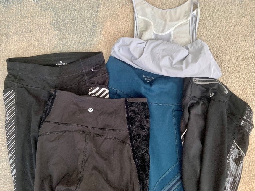 Athleta athletic leggings in black, gray, and teal with a light gray mesh top laid on a beige carpet.