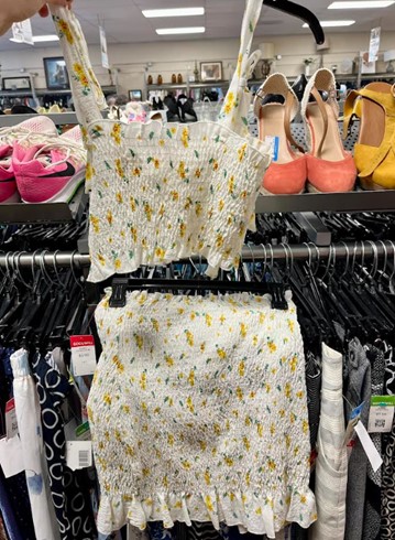 White floral two-piece crop top and skirt set with small yellow flowers on display in a clothing store.