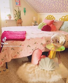 a bed with pink comforter and a pink throw blanked and pillows. 