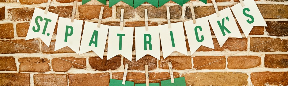 Green lettered pennant banner spelling ST. PATRICK'S against a brick wall.