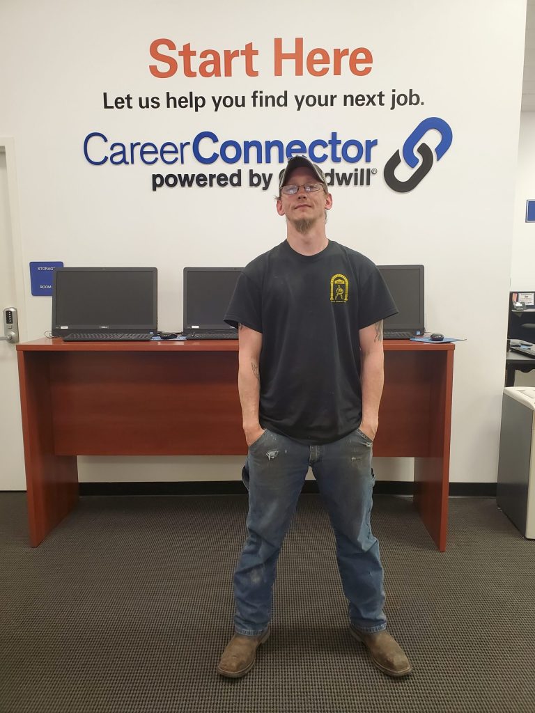Man stands with hands in pockets in front of a CareerConnector sign at a job center.