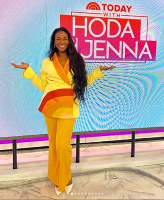 Smiling woman in a bright yellow suit with orange accents poses in front of a 'Today with Hoda & Jenna' backdrop.