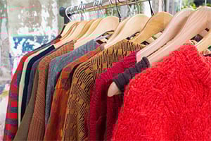 Colorful knit sweaters on wooden hangers in a clothing store