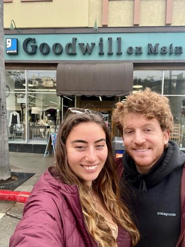 Two people pose for a selfie in front of a Goodwill store on Main Street.