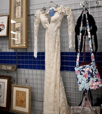 White lace wedding dress on a dress form in a thrift shop display