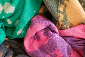 Colorful folded fabrics including teal, green, purple, and pink with tie-dye patterns.