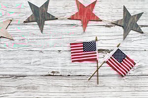 Rustic wooden surface with star bunting and small American flags.