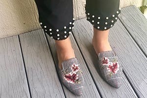 Gray woven slip-on shoes with red dragon embroidery, paired with polka-dot pants, on a wooden deck.