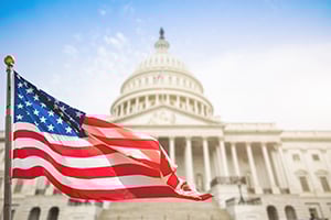American flag waving in front of the U.S. Capitol dome