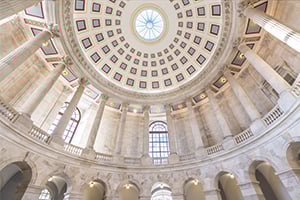 Interior rotunda with a coffered dome, circular oculus, and arched colonnade of tall columns.