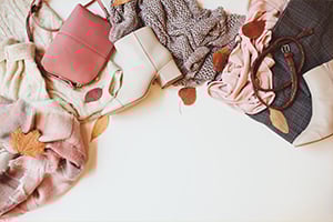 Flat lay of multiple fashion accessories including handbags and scarves on a white background.