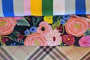 Fabric patterns: color-striped edge, dark floral print with pink roses, and plaid.