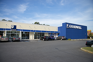 Goodwill storefront with blue sign and parked cars in front of the entrance.