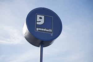 Blue circular sign on a pole with a white square logo featuring a stylized curved symbol.