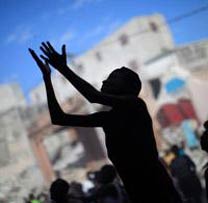 Silhouette of a person with raised hands amid a crowd against a graffiti-covered wall.